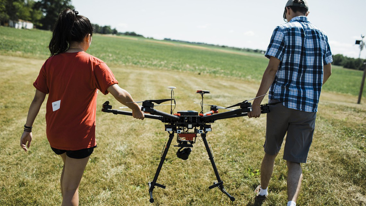 Students Ami Mineta ’19 and James Gustafson ’21 carry a drone at Musgrave Research Farm.